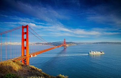 Suspension bridge over sea against sky