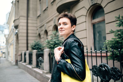 Portrait of young woman standing on street in city