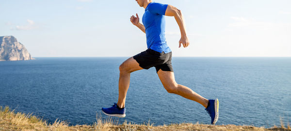 Male athlete running on sea background