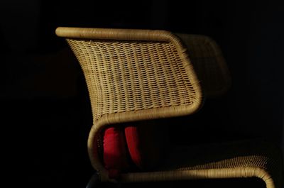 Close-up of wicker chair against black background