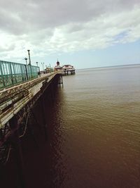 Pier on sea against cloudy sky