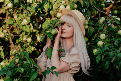 Portrait of young woman against tree