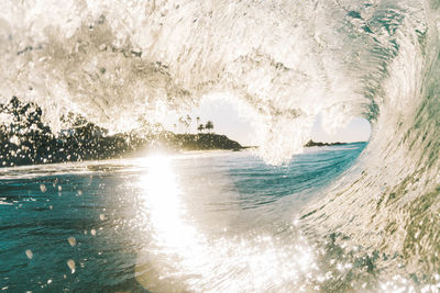 Sea waves splashing on shore against sky