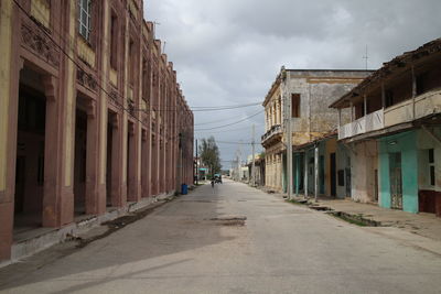 Empty road amidst buildings in city against sky