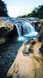 Scenic view of waterfall against sky