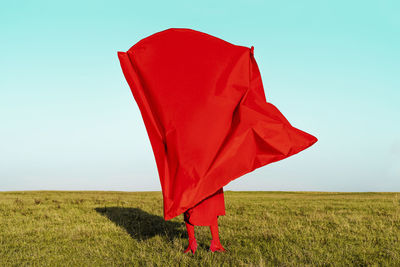 Red umbrella on field against clear sky