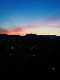 Illuminated cityscape against sky at sunset