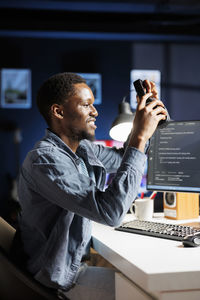 Side view of man using mobile phone in office