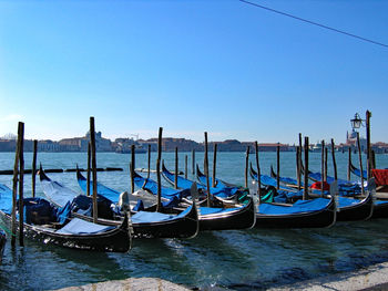 Boats moored in canal against blue sky