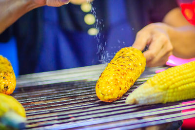 Midsection of man roasting corns