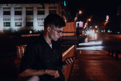 Young man looking away in city at night