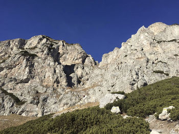 Low angle view of rocks against clear blue sky