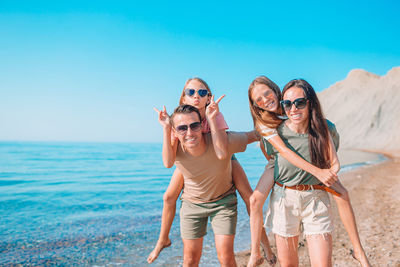 Portrait of friends standing by sea against sky