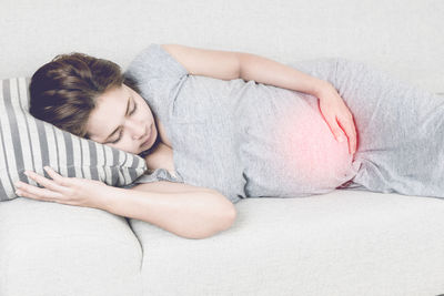 Pregnant young woman sleeping on sofa at home