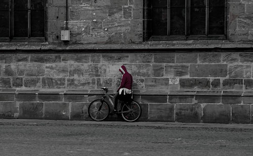 Man riding bicycle on street against building