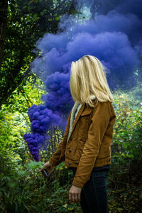 Woman looking away while standing on tree