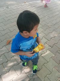 High angle view of boy eating food on street