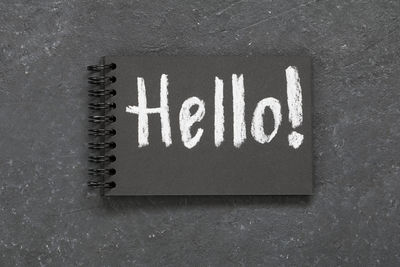 High angle view of hello text on spiral notebook over gray background