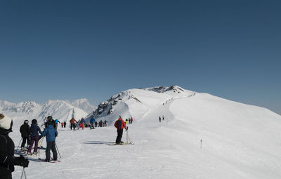 People in snow covered mountain against blue sky