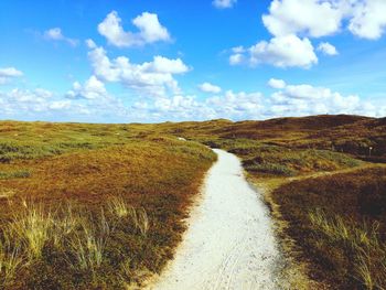 Scenic view of road amidst field against sky