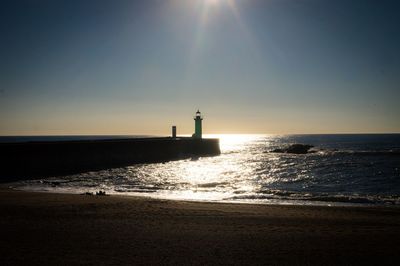 Lighthouse by sea against sky