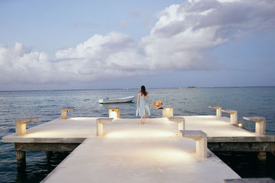 Rear view of woman by sea against sky