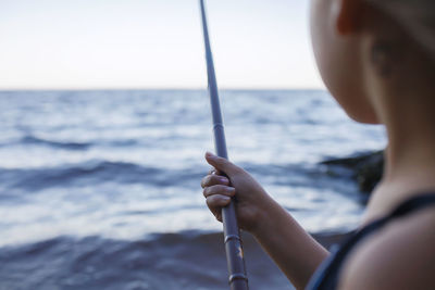 Close-up of woman holding sunglasses against sea