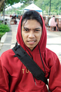 Close-up portrait of young man in hooded shirt outdoors