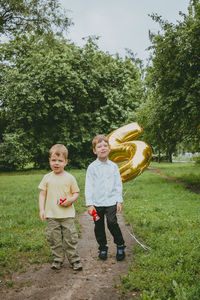 2 boys in the park are photographed in honor of their birthday, against a background of confetti.