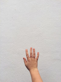 Close-up of hand against white wall