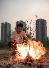 Man spraying liquid on fire against buildings at field