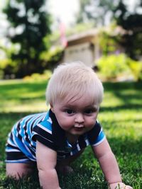 Close-up of cute baby boy crawling on grassy field