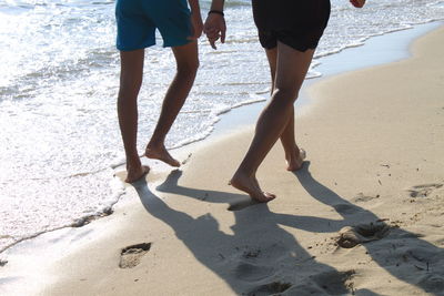 Low section of people walking on beach