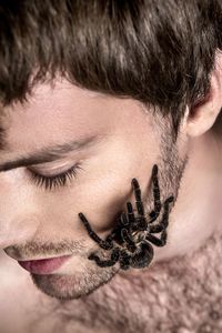 Close-up of scared man with tarantula on face