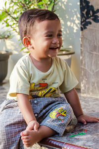 Cute boy sitting on bed at home