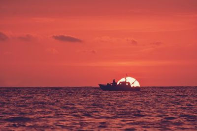 Silhouette boat in sea against sky during sunset