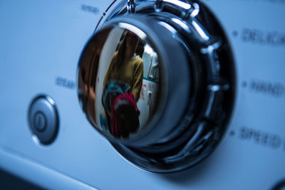 Woman reflecting on knob of washing machine