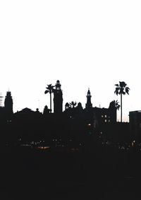 Silhouette buildings against clear sky at dusk