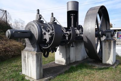 Close-up of machinery on field against sky