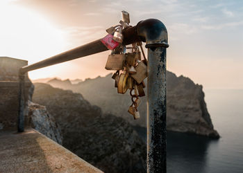 Close-up of chain hanging on pole by sea against sky