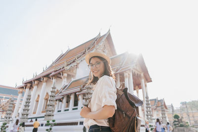 Woman standing against buildings in city against clear sky