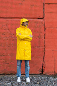 Full length of man wearing raincoat standing against wall