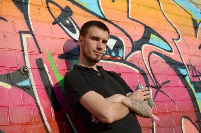 Young man standing against graffiti wall