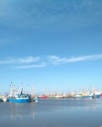 Boats moored at harbor against sky