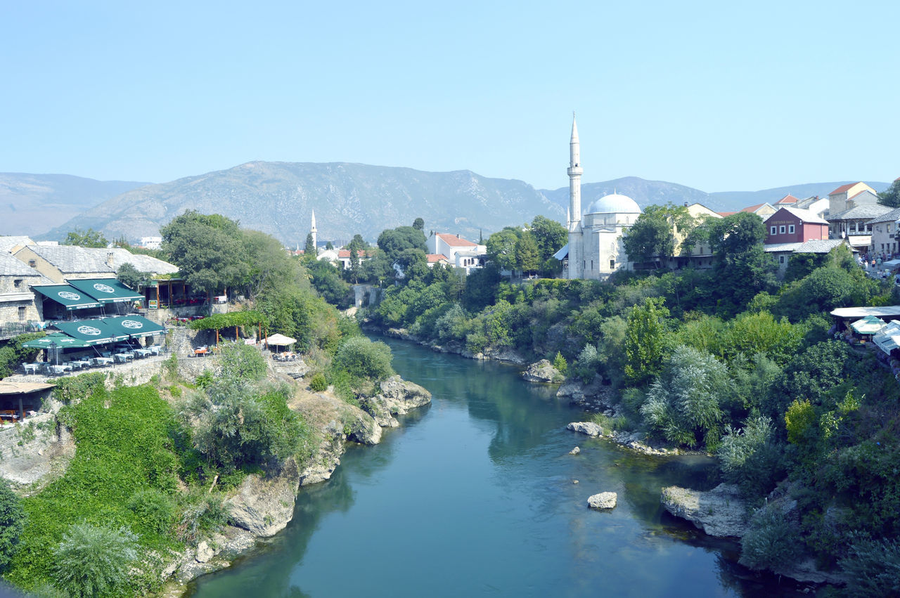 SCENIC VIEW OF RIVER BY TOWN AGAINST SKY