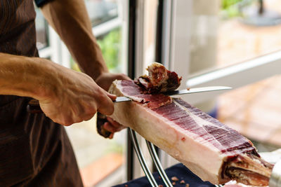 Midsection of man cutting meat