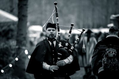 Man playing bagpipe while standing outdoors