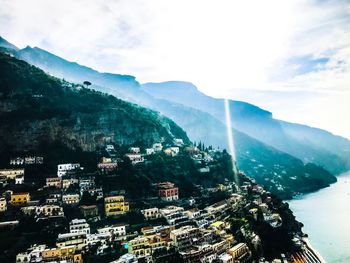 Aerial view of townscape by mountains against sky