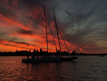 Silhouette sailboats in sea against sky during sunset