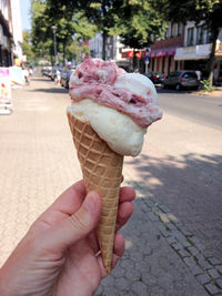 Hand holding ice cream cone on street